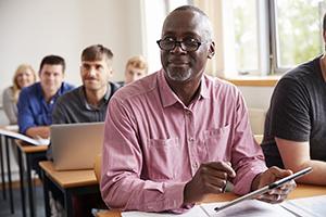 Mature Student Using Digital Tablet In Adult Education Class